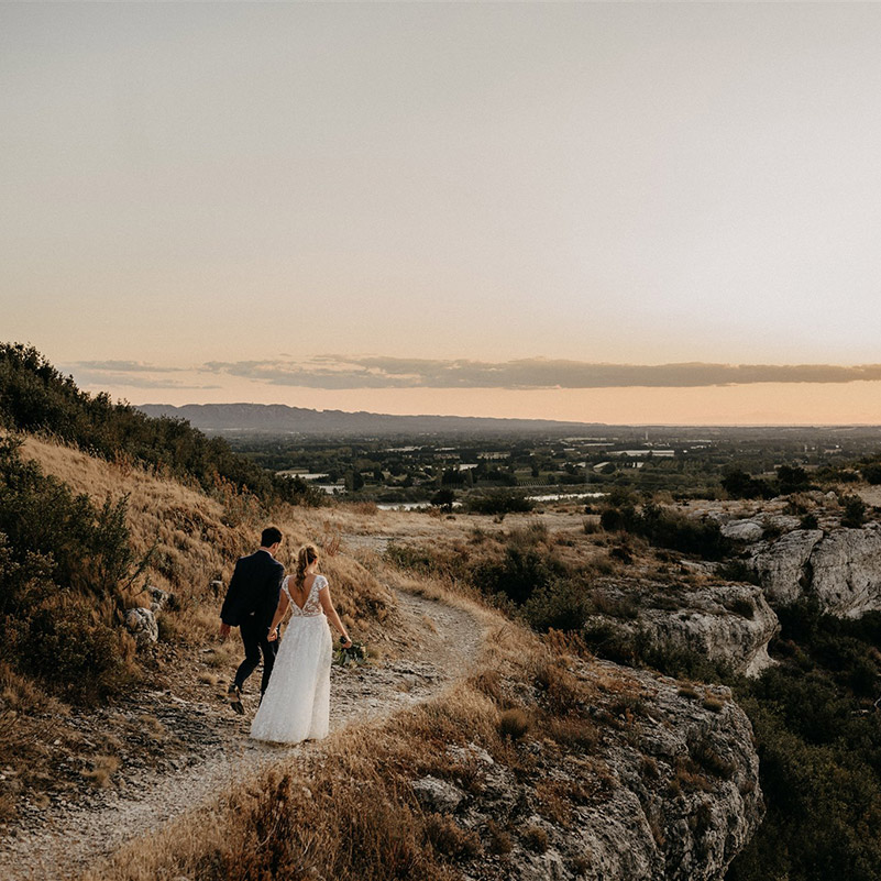 Mariés se tenant la main et marchant sur un sentier